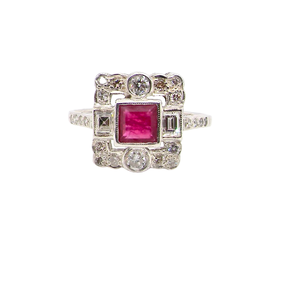 An Art Deco style cluster ring. Set to the centre a square 5x5mm ruby, rub over setting and complimented by a surround of white diamonds.