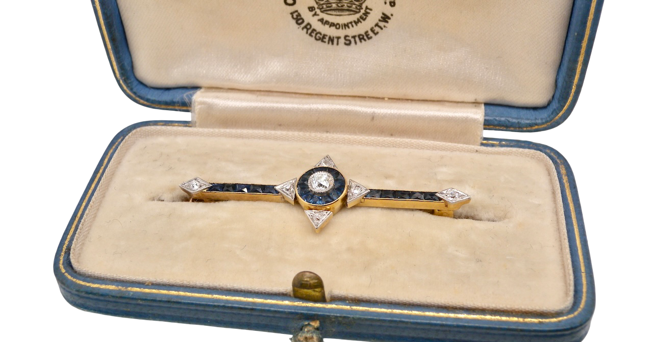 An Edwardian bar brooch. The centre 'target' style portion is set with a brilliant cut white diamond 4mm (0.25 carats) Mille grain setting.