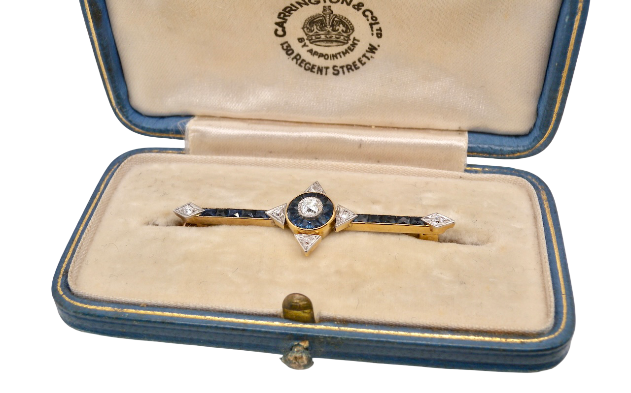 An Edwardian bar brooch. The centre 'target' style portion is set with a brilliant cut white diamond 4mm (0.25 carats) Mille grain setting.