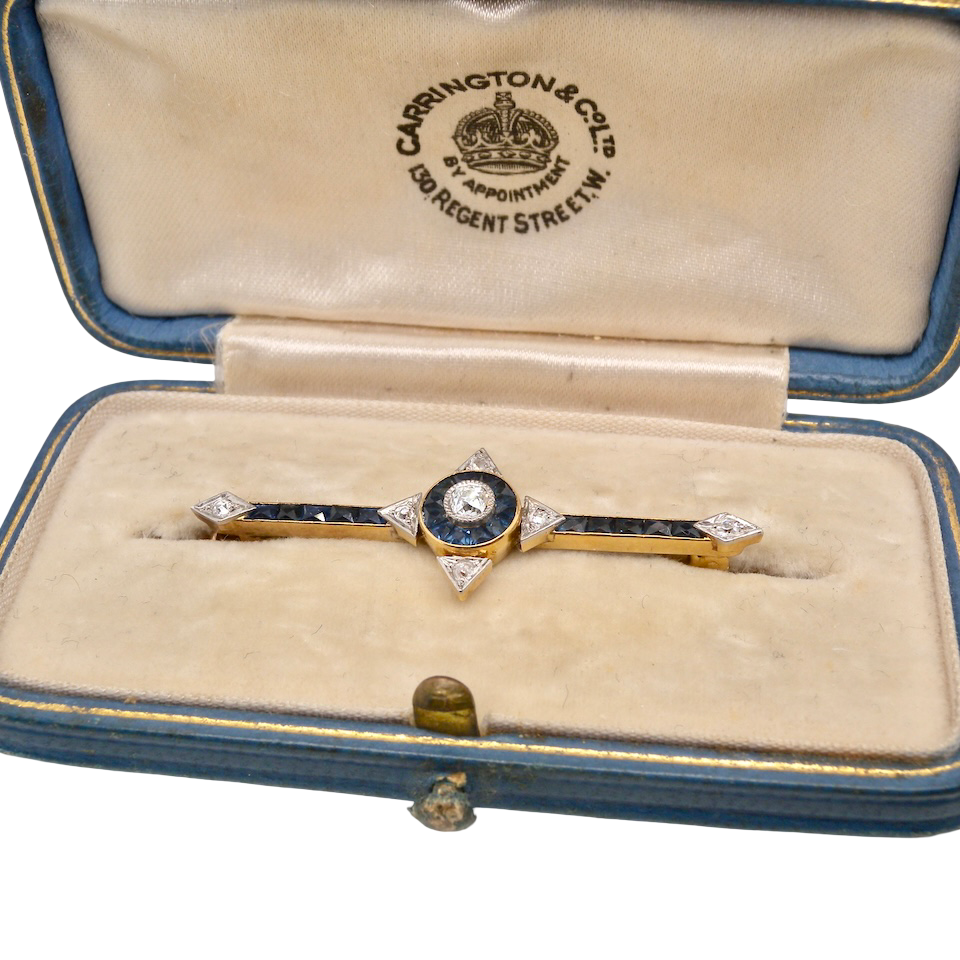 An Edwardian bar brooch. The centre 'target' style portion is set with a brilliant cut white diamond 4mm (0.25 carats) Mille grain setting.
