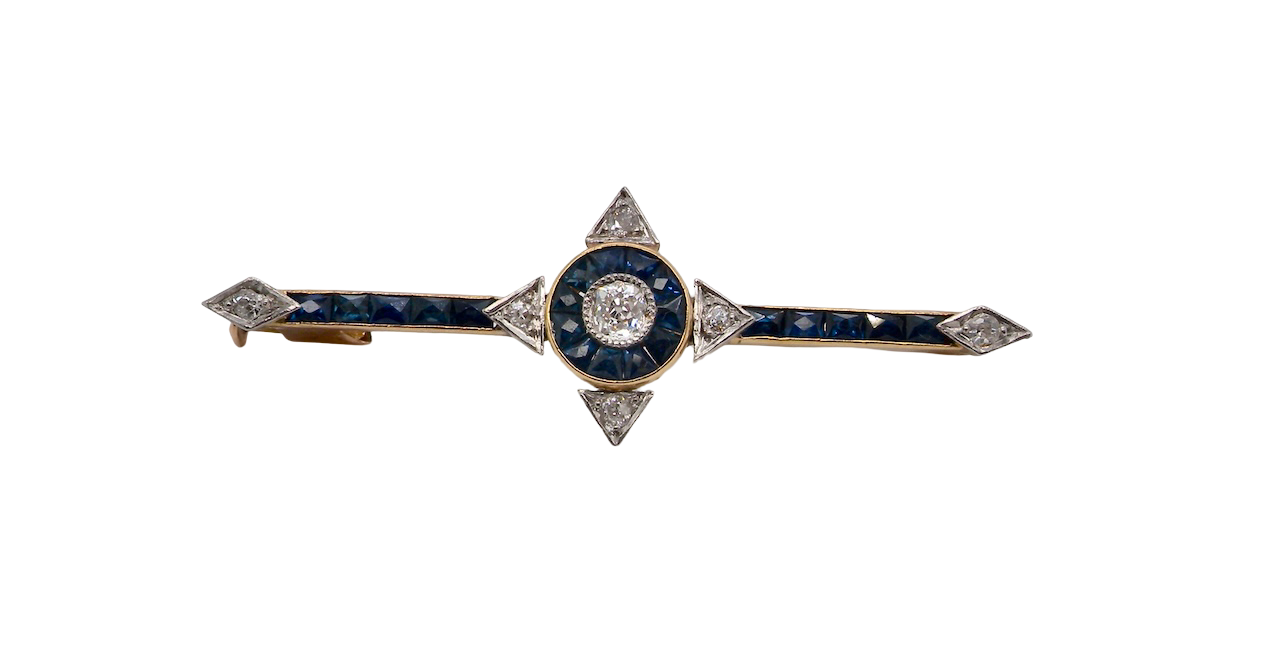 An Edwardian bar brooch. The centre 'target' style portion is set with a brilliant cut white diamond 4mm (0.25 carats) colour H-j, clarity Si. Mille grain setting.