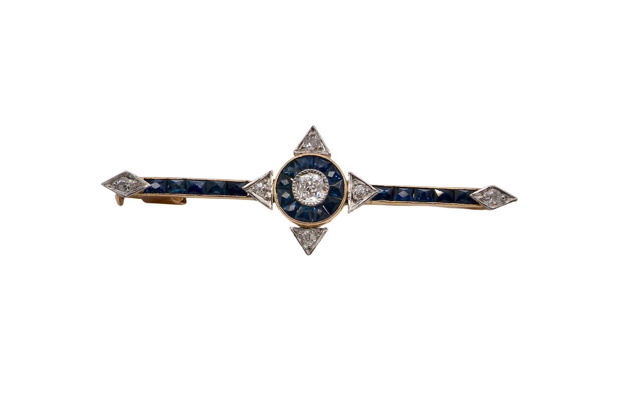 An Edwardian bar brooch. The centre 'target' style portion is set with a brilliant cut white diamond 4mm (0.25 carats) colour H-j, clarity Si. Mille grain setting.