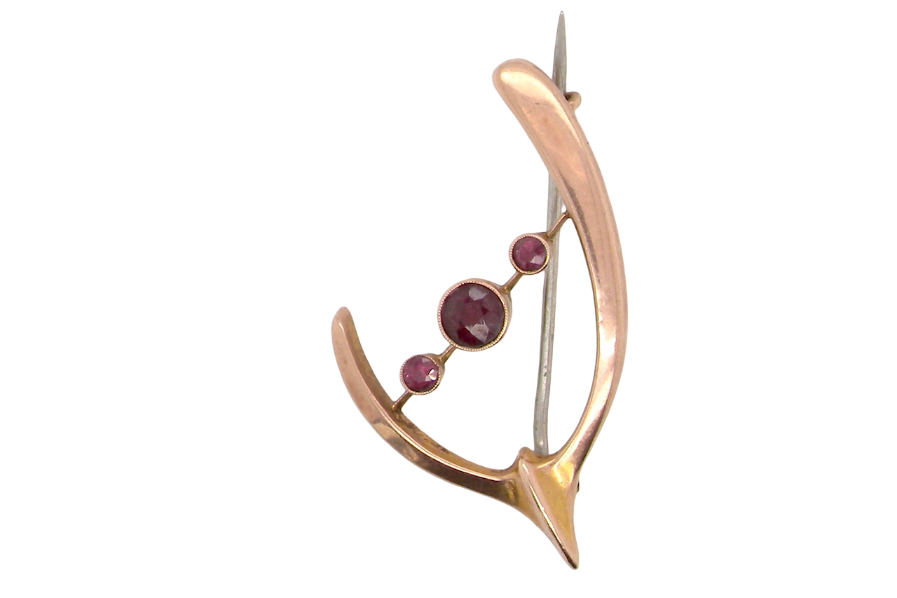 Gold brooch with embedded gemstones on a white background
