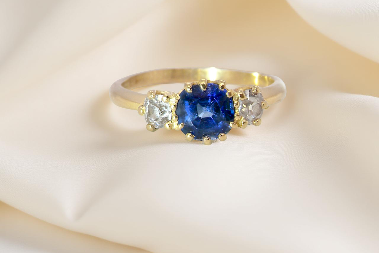 An early 20th-century trilogy ring set with a mid to dark cornflower blue sapphire,