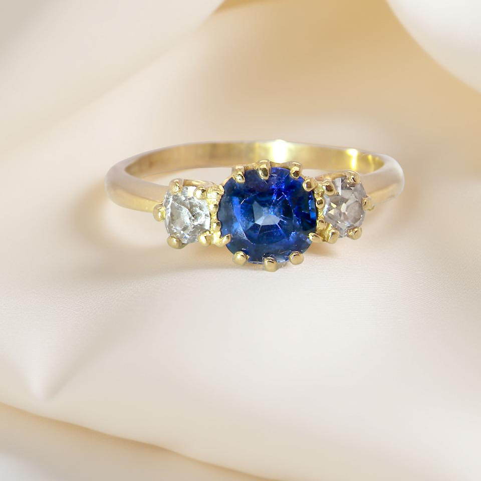 An early 20th-century trilogy ring set with a mid to dark cornflower blue sapphire,