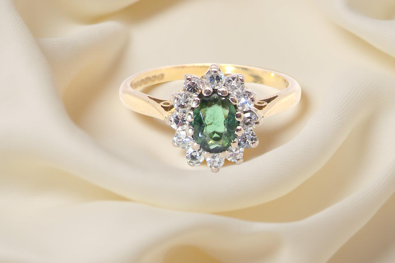 An elegant 18 carat gold cluster ring featuring a beautifully proportioned green tourmaline