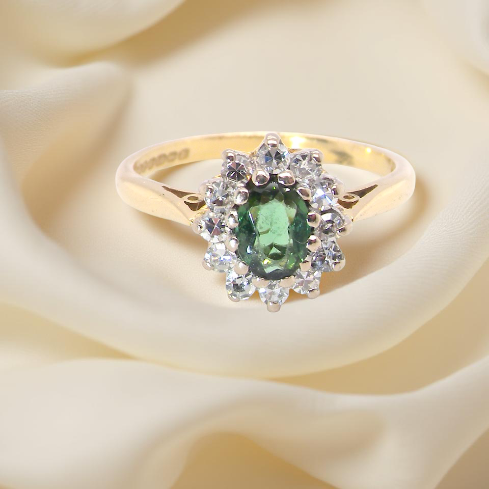 An elegant 18 carat gold cluster ring featuring a beautifully proportioned green tourmaline