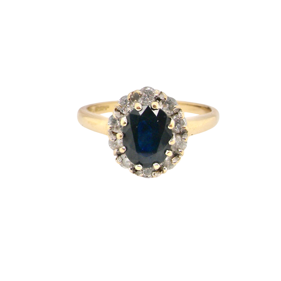 An elegant 18 carat gold cluster ring featuring a striking inky dark blue sapphire at its centre.