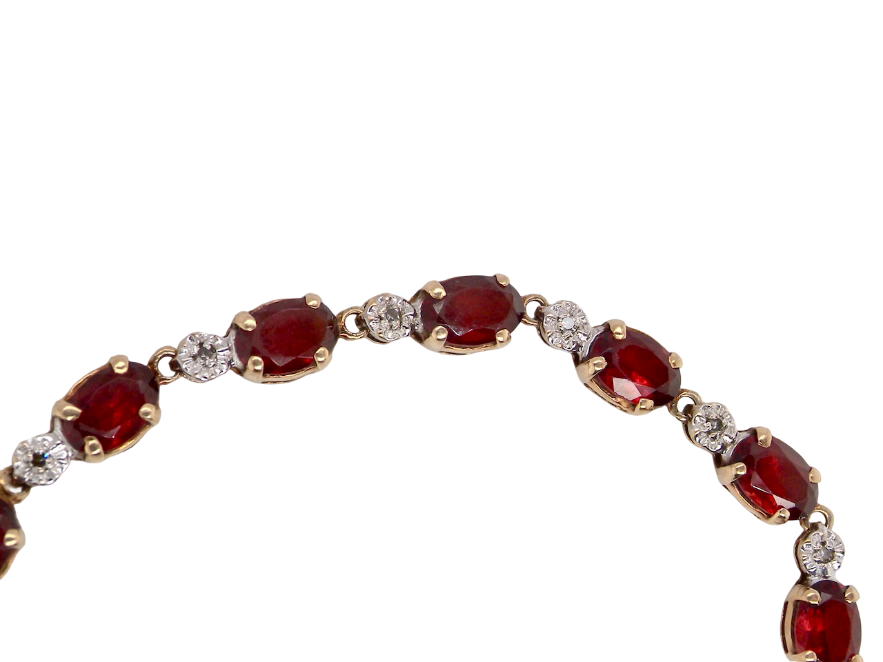 An elegant 9 carat gold bracelet set with sixteen rich red oval-cut garnets, each measuring approximately 6 x 4mm. Between each garnet sits a delicate illusion-set diamond in white gold, creating the appearance of larger stones