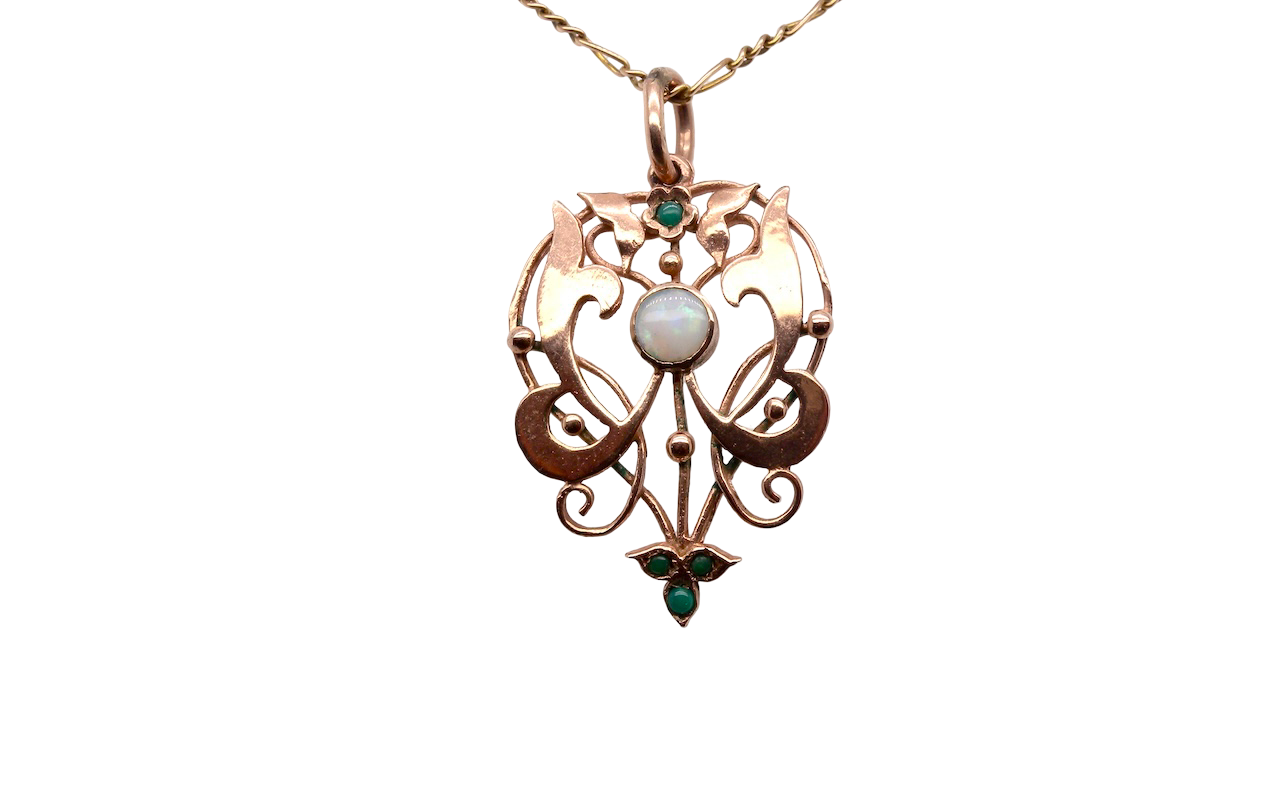 An elegant Edwardian-style pendant featuring a fancy openwork design, set with a round 5mm opal centre stone.