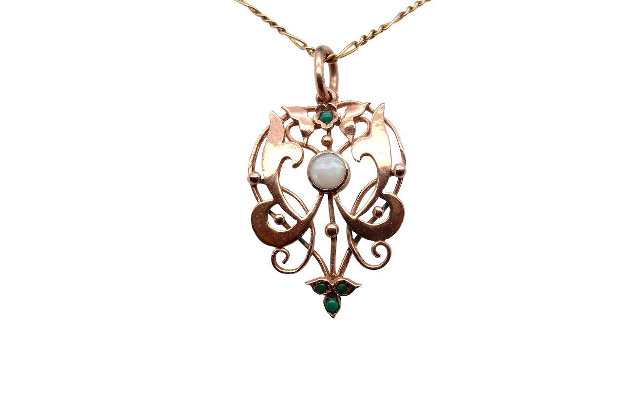 An elegant Edwardian-style pendant featuring a fancy openwork design, set with a round 5mm opal centre stone.