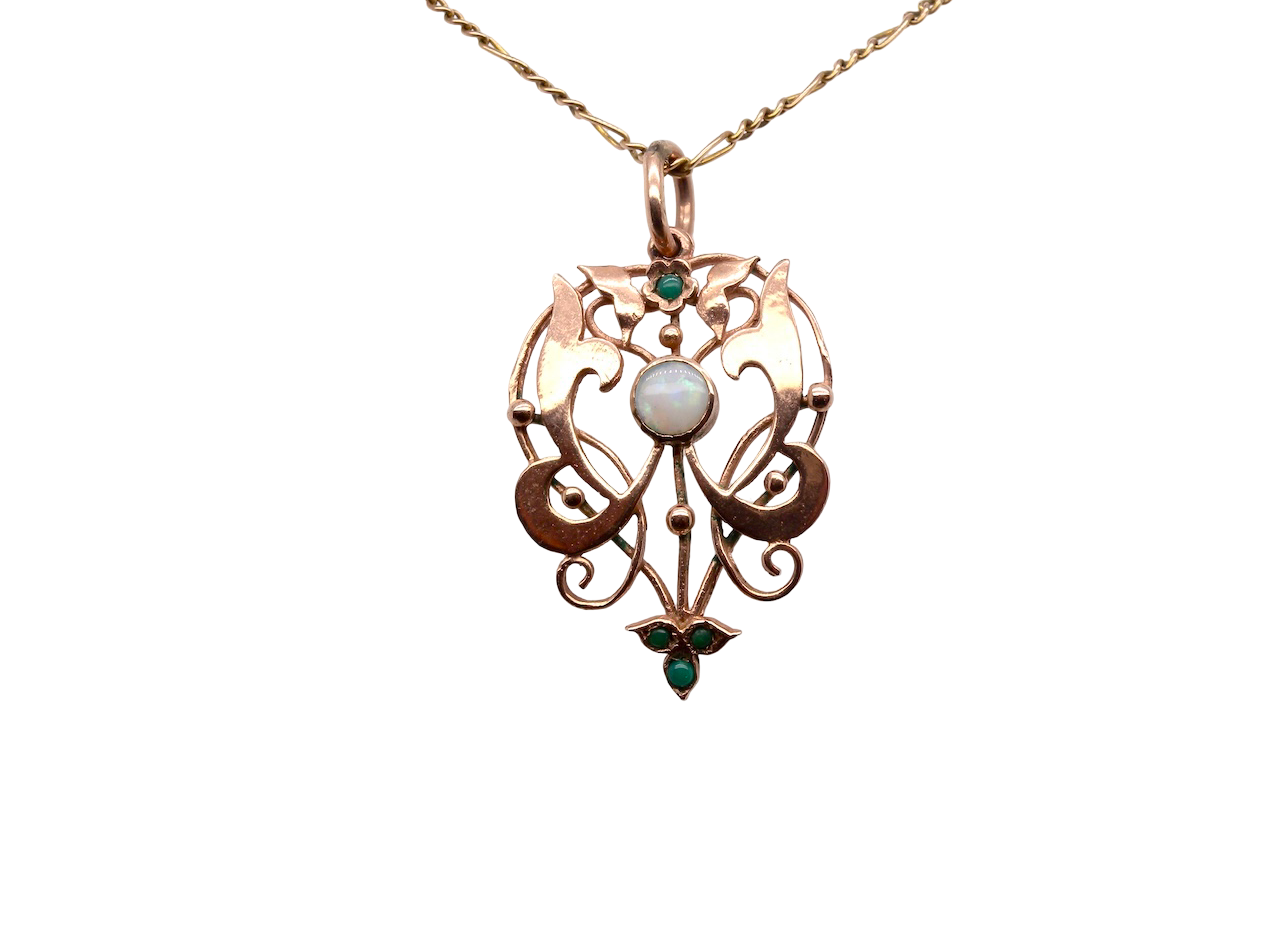 An elegant Edwardian-style pendant featuring a fancy openwork design, set with a round 5mm opal centre stone.
