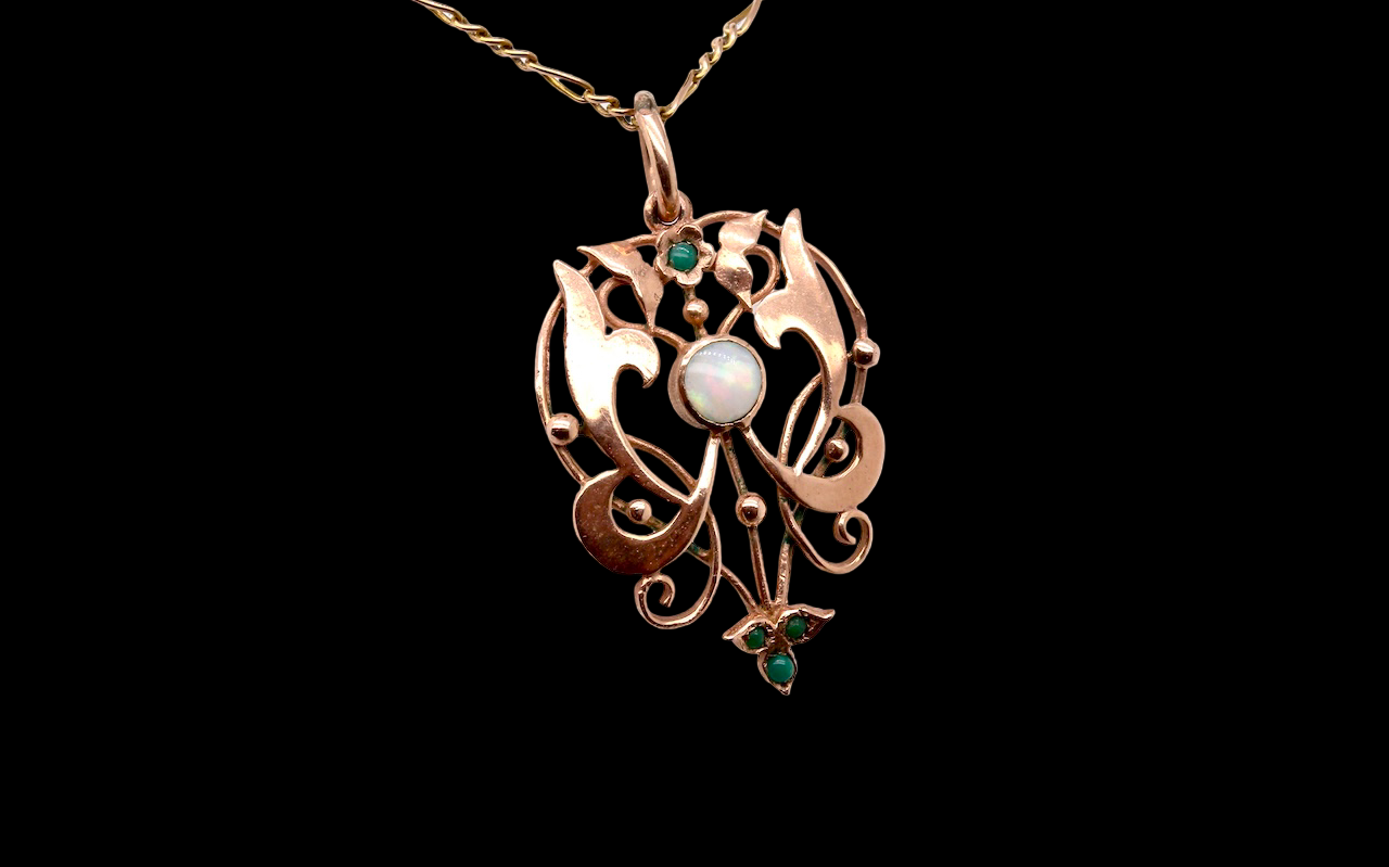 An elegant Edwardian-style pendant featuring a fancy openwork design, set with a round opal centre stone.