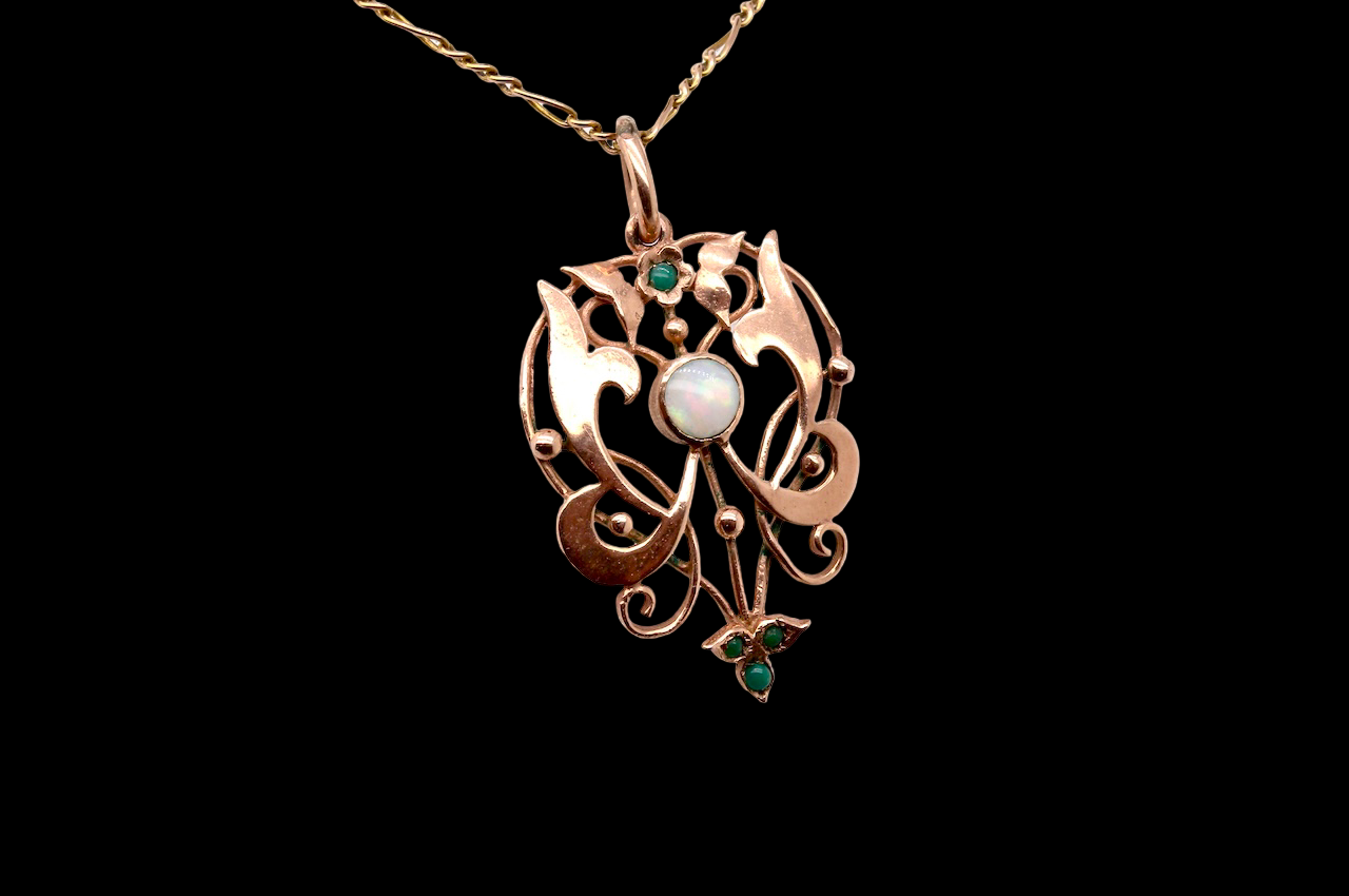 An elegant Edwardian-style pendant featuring a fancy openwork design, set with a round opal centre stone.