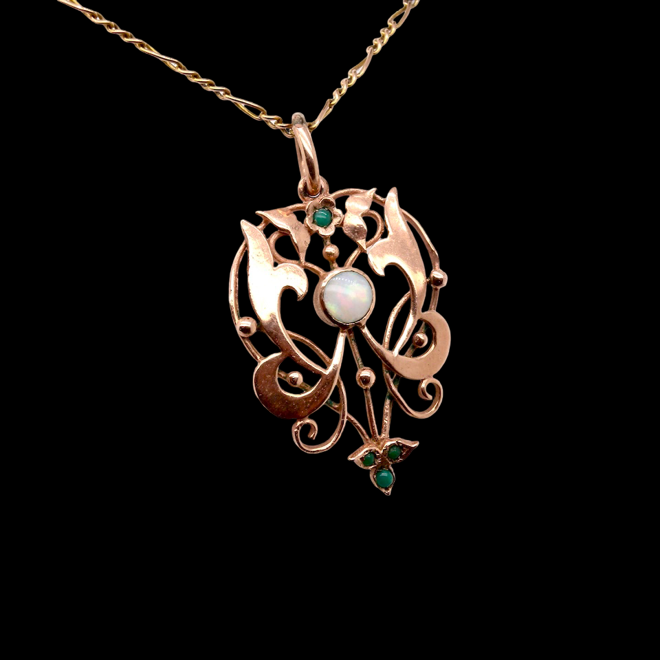 An elegant Edwardian-style pendant featuring a fancy openwork design, set with a round opal centre stone.