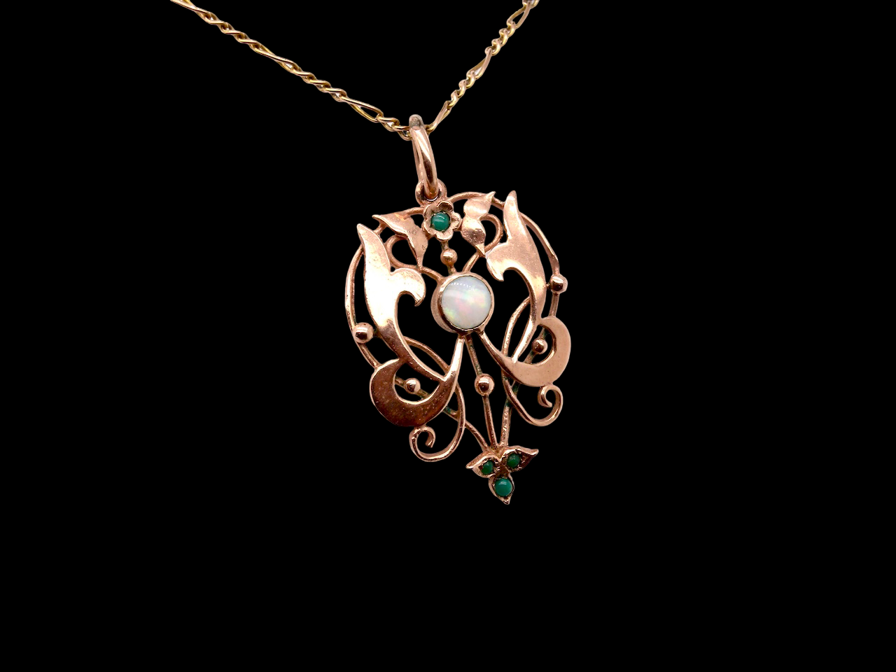 An elegant Edwardian-style pendant featuring a fancy openwork design, set with a round opal centre stone.