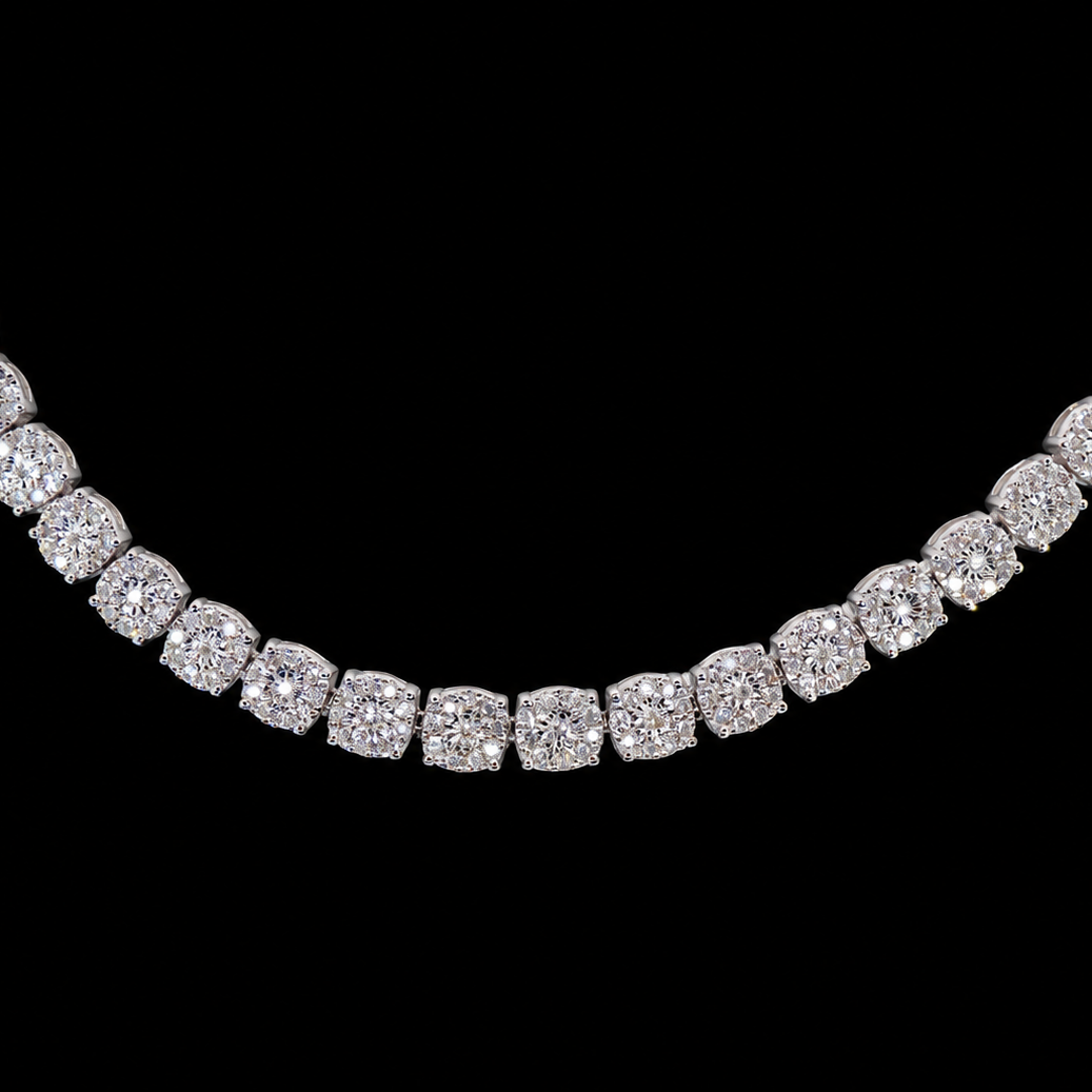 A diamond tennis necklace with cushion-cut diamonds set in a silver-toned metal, shown against a solid black background.