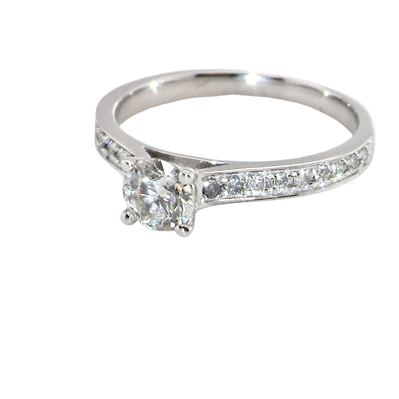 A diamond engagement ring with a round-cut center stone and a pavé-set diamond band, shown on a plain white background.