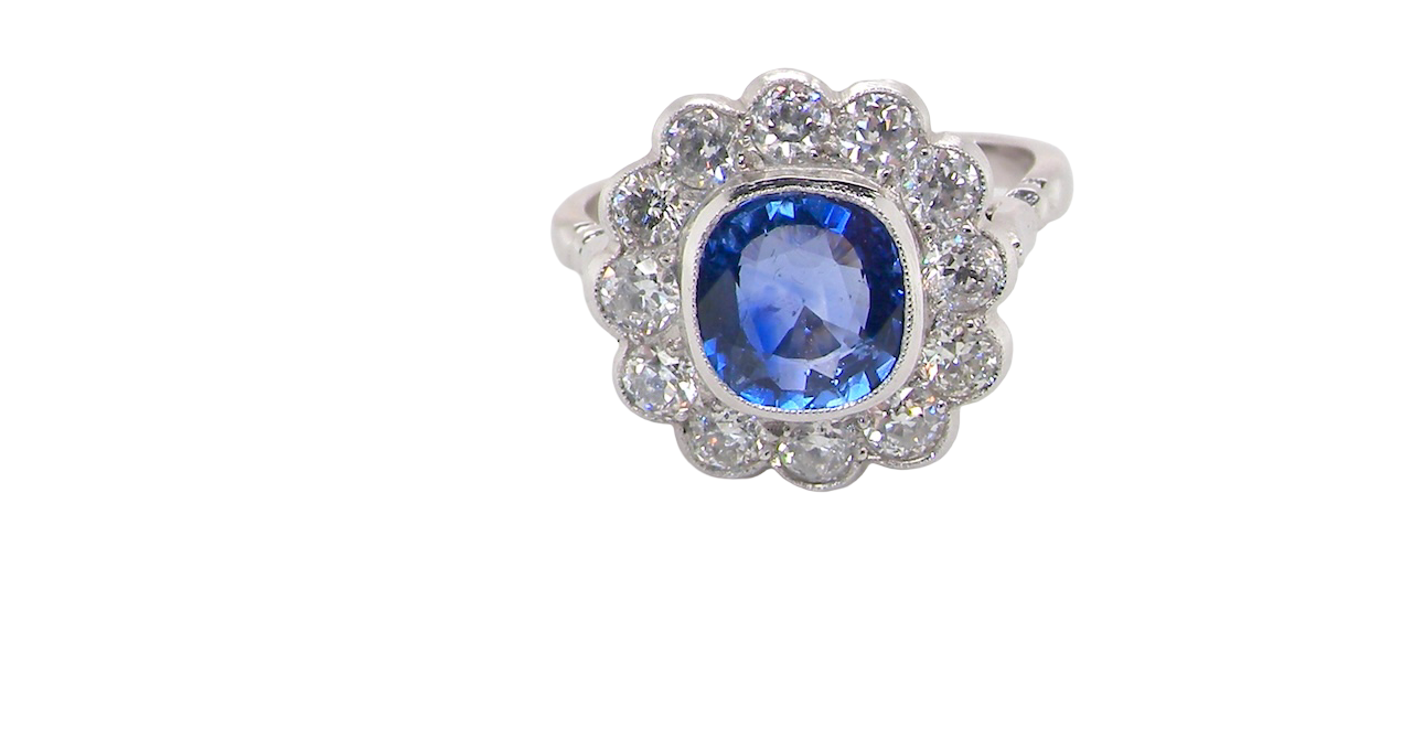 An elegant and timeless cluster ring, centrally set with a beautiful mid to deep blue cushion-cut sapphire, measuring approximately 8 x 8mm (est 2.00 carats).