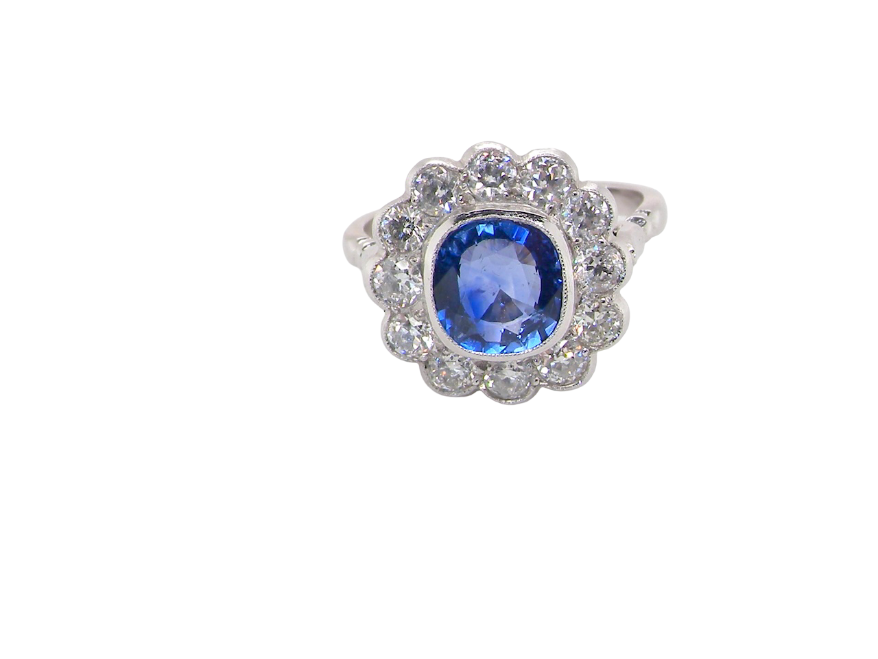 An elegant and timeless cluster ring, centrally set with a beautiful mid to deep blue cushion-cut sapphire, measuring approximately 8 x 8mm (est 2.00 carats).