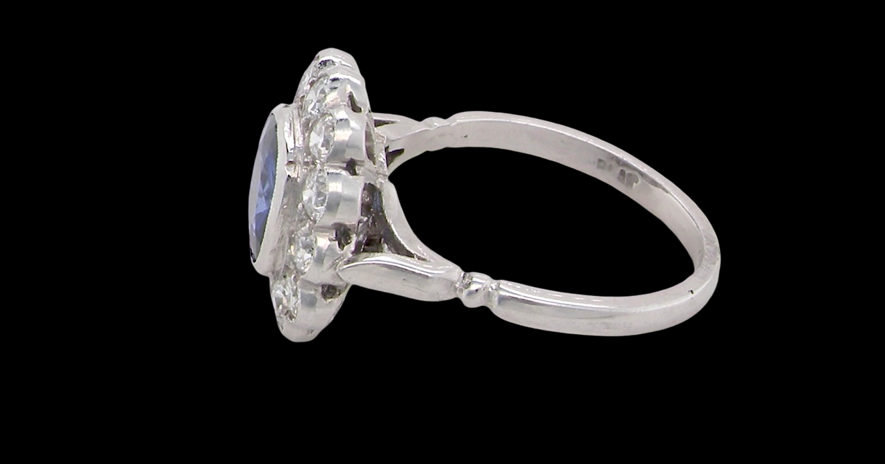 An elegant and timeless cluster ring, centrally set with a beautiful mid to deep blue cushion-cut sapphire, measuring approximately 8 x 8mm (estimated 2.00 carats). side
