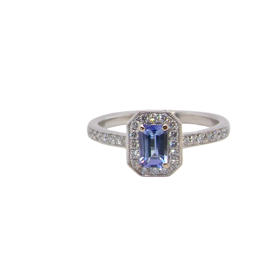 An elegant cluster ring that features to the centre a rectangular tanzanite gemstone that measures 6x4mm (est 0.50 carats) AAA colour.