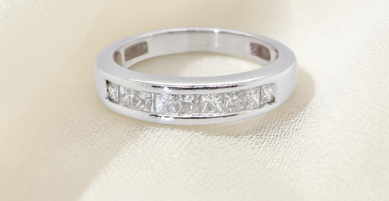 An elegant half-hoop eternity ring set with nine princess-cut white diamonds, each measuring approximately 2.5mm, with a total diamond weight of 0.90 carats.
