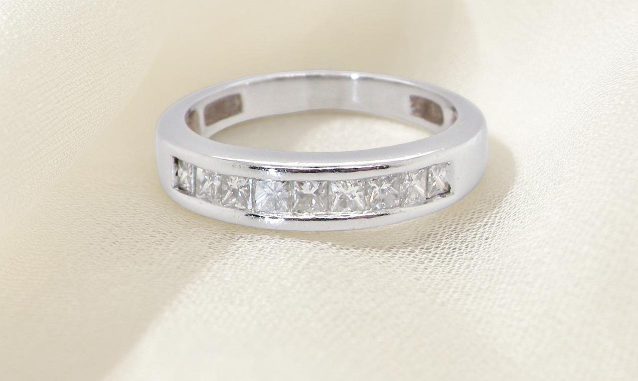 An elegant half-hoop eternity ring set with nine princess-cut white diamonds, each measuring approximately 2.5mm, with a total diamond weight of 0.90 carats.