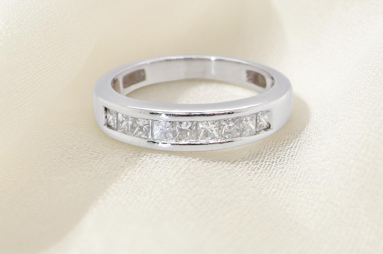 An elegant half-hoop eternity ring set with nine princess-cut white diamonds, each measuring approximately 2.5mm, with a total diamond weight of 0.90 carats.