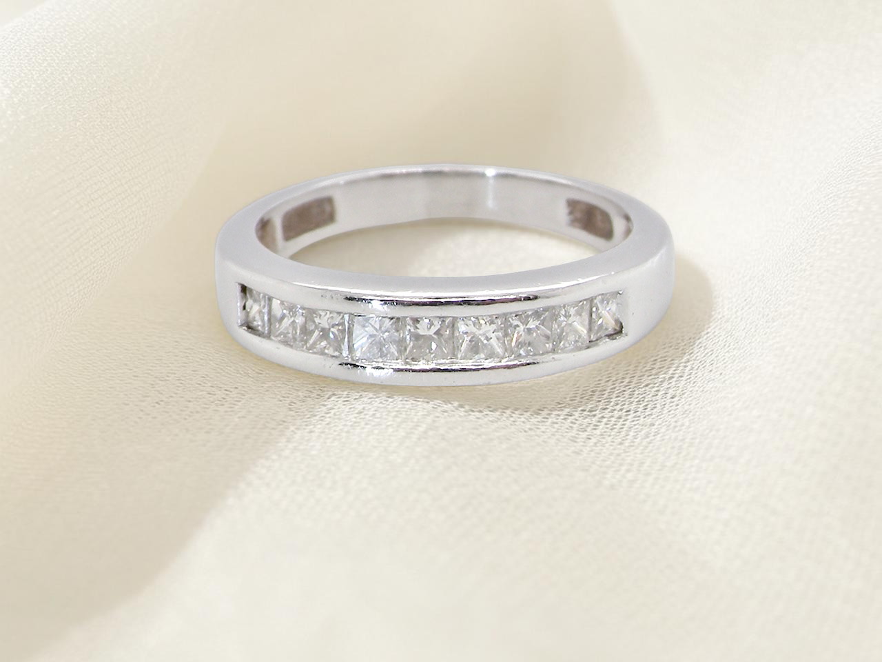 An elegant half-hoop eternity ring set with nine princess-cut white diamonds, each measuring approximately 2.5mm, with a total diamond weight of 0.90 carats.