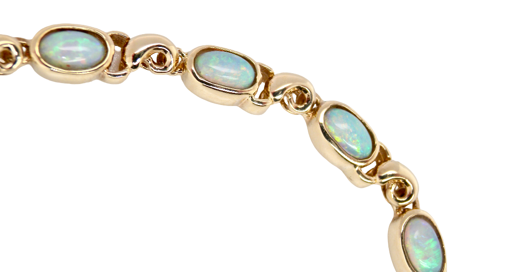 An elegant line bracelet set with fourteen oval opals, each measuring approximately 5 x 3 mm, displaying a good and lively play of colour.