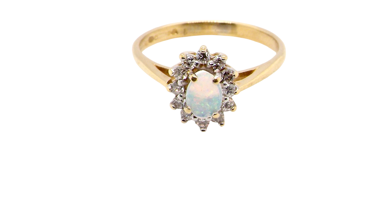 An elegant cluster ring featuring a white opal centre stone measuring 6 × 4mm, displaying a lively and attractive play of colour.