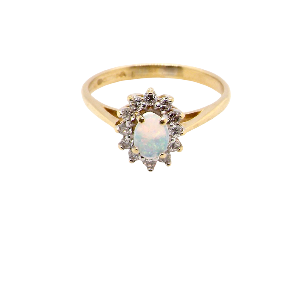 An elegant cluster ring featuring a white opal centre stone measuring 6 × 4mm, displaying a lively and attractive play of colour.