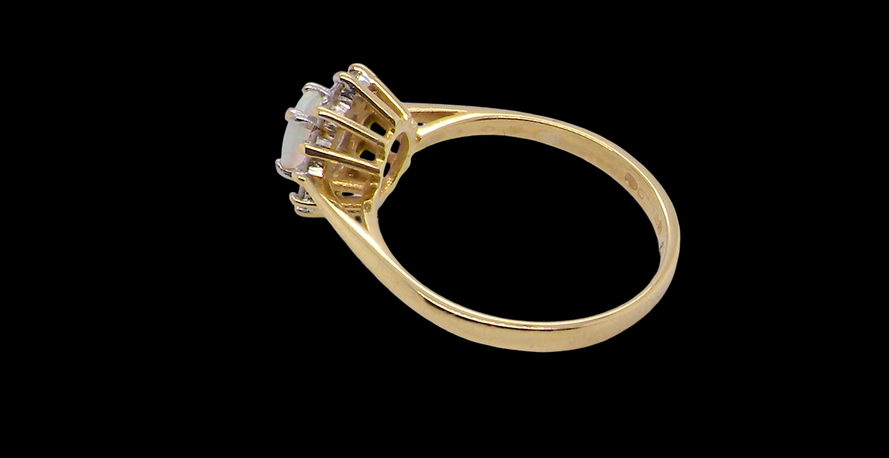 An elegant cluster ring featuring a white opal centre stone measuring 6 × 4mm, displaying a lively and attractive play of colour. side