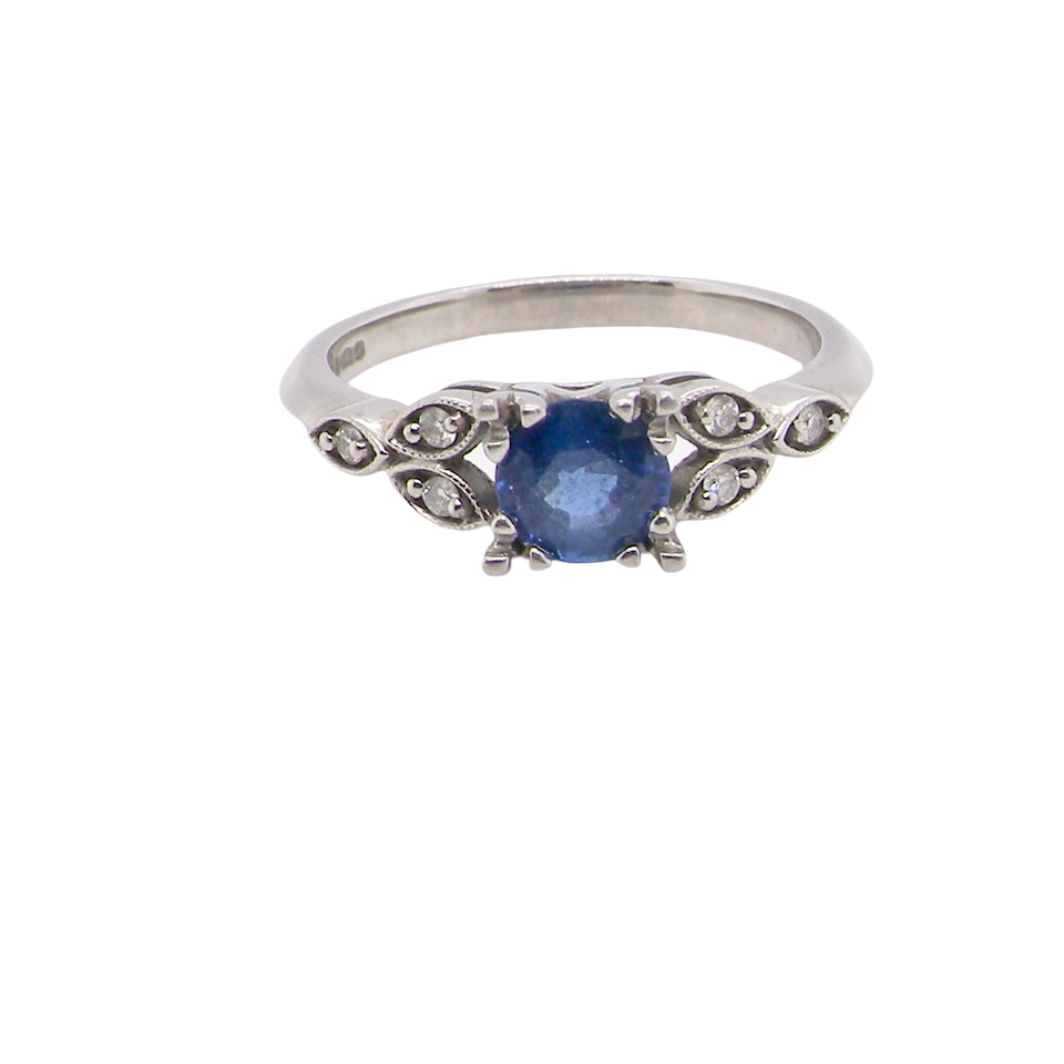 An elegant vintage-style platinum ring showcasing a beautifully proportioned round sapphire with a soft mid to light cornflower blue hue. The sapphire measures 5.6mm in diameter (approx. 0.80 carats)