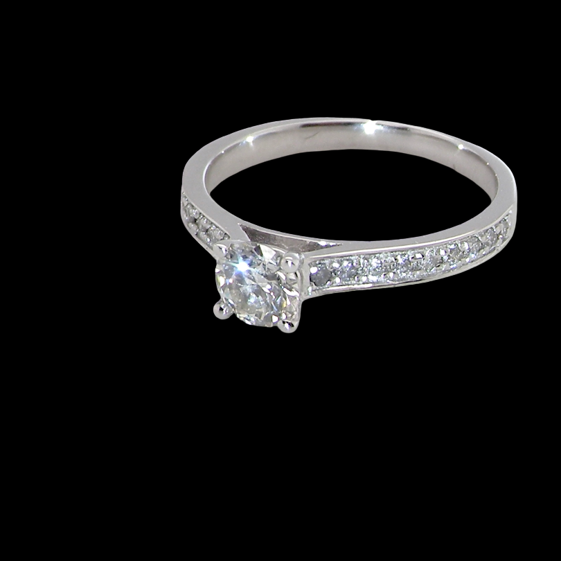 A diamond engagement ring with a round center stone and pavé-set diamonds on the band, shown against a solid black background.