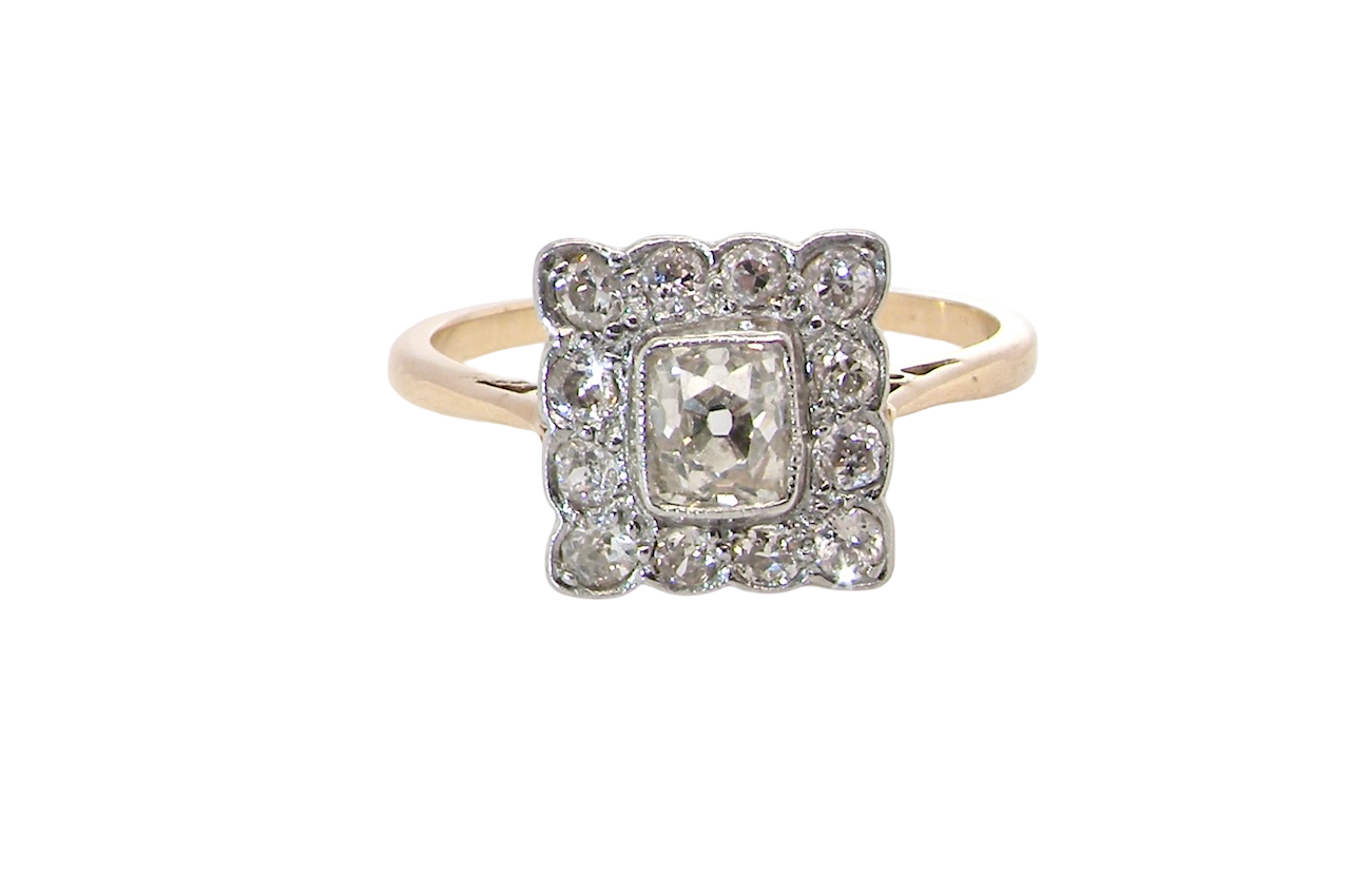 An exquisite Art Deco diamond cluster ring, beautifully handcrafted and rich in period charm.
At its centre sits a striking rectangular cut diamond measuring approximately 5 x 4.8mm,