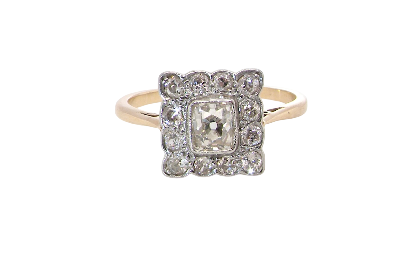 An exquisite Art Deco diamond cluster ring, beautifully handcrafted and rich in period charm.
At its centre sits a striking rectangular cut diamond measuring approximately 5 x 4.8mm,