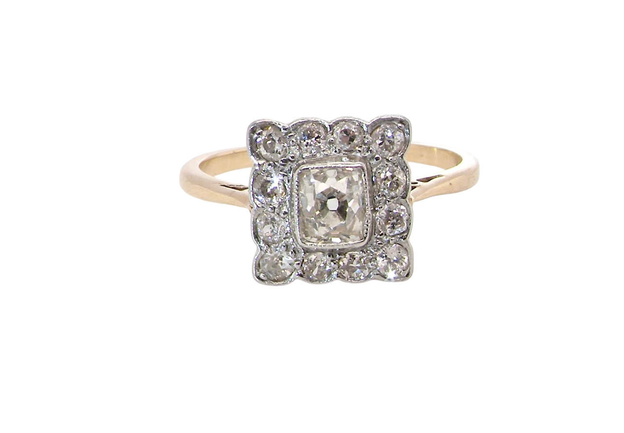An exquisite Art Deco diamond cluster ring, beautifully handcrafted and rich in period charm.
At its centre sits a striking rectangular cut diamond measuring approximately 5 x 4.8mm,