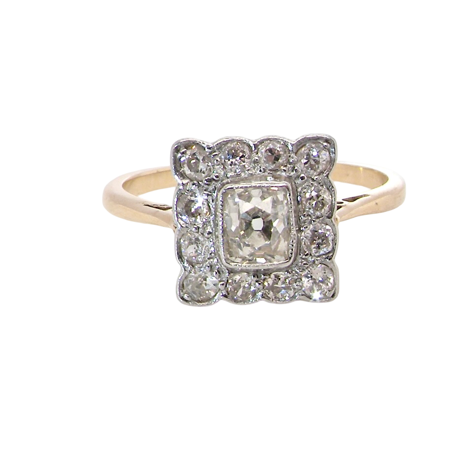 An exquisite Art Deco diamond cluster ring, beautifully handcrafted and rich in period charm.
At its centre sits a striking rectangular cut diamond measuring approximately 5 x 4.8mm,