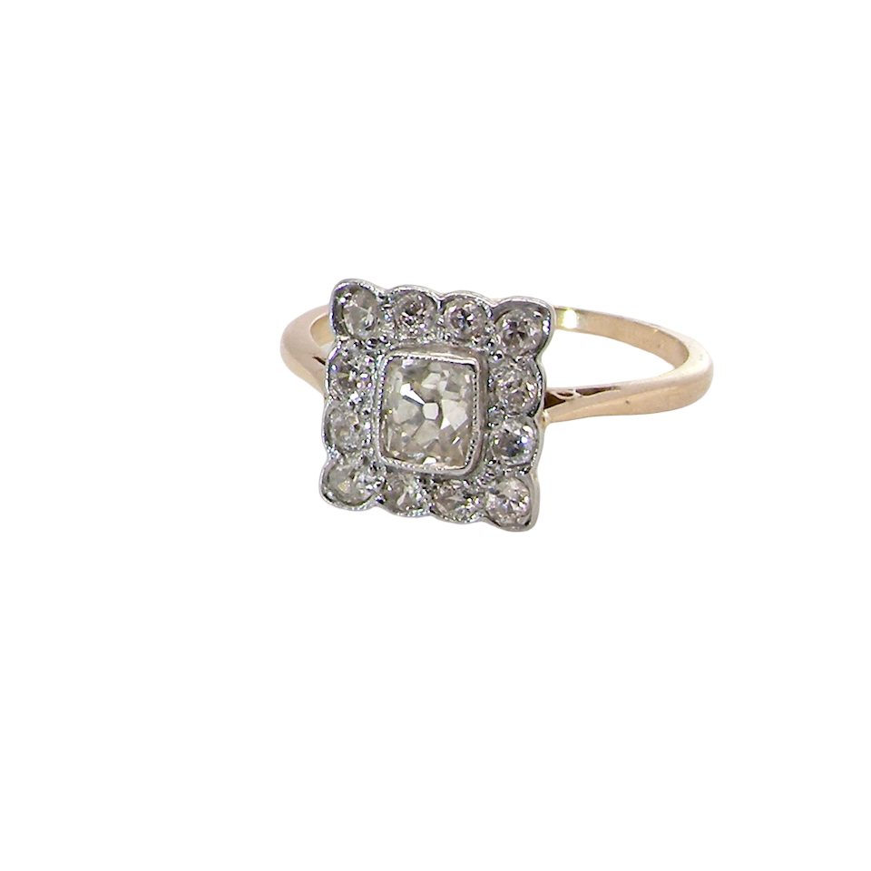 An exquisite Art Deco diamond cluster ring, beautifully handcrafted and rich in period charm.
At its centre sits a striking rectangular cut diamond measuring approximately 5 x 4.8mm, estimated at 0.50 carats,