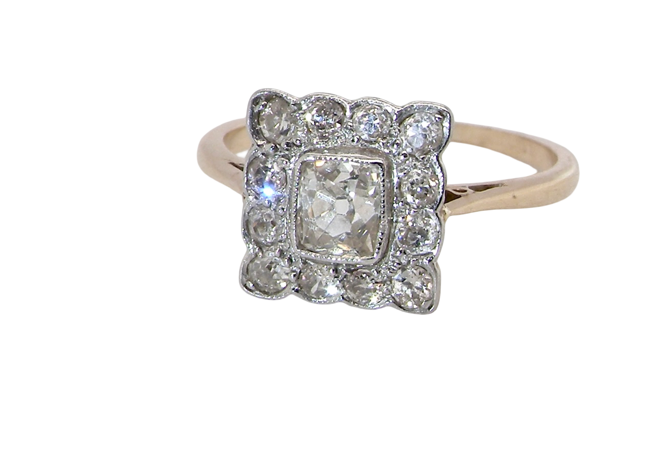 An exquisite Art Deco diamond cluster ring, beautifully handcrafted and rich in period charm.
At its centre sits a striking rectangular cut diamond measuring approximately 5 x 4.8mm, estimated at 0.50 carats,