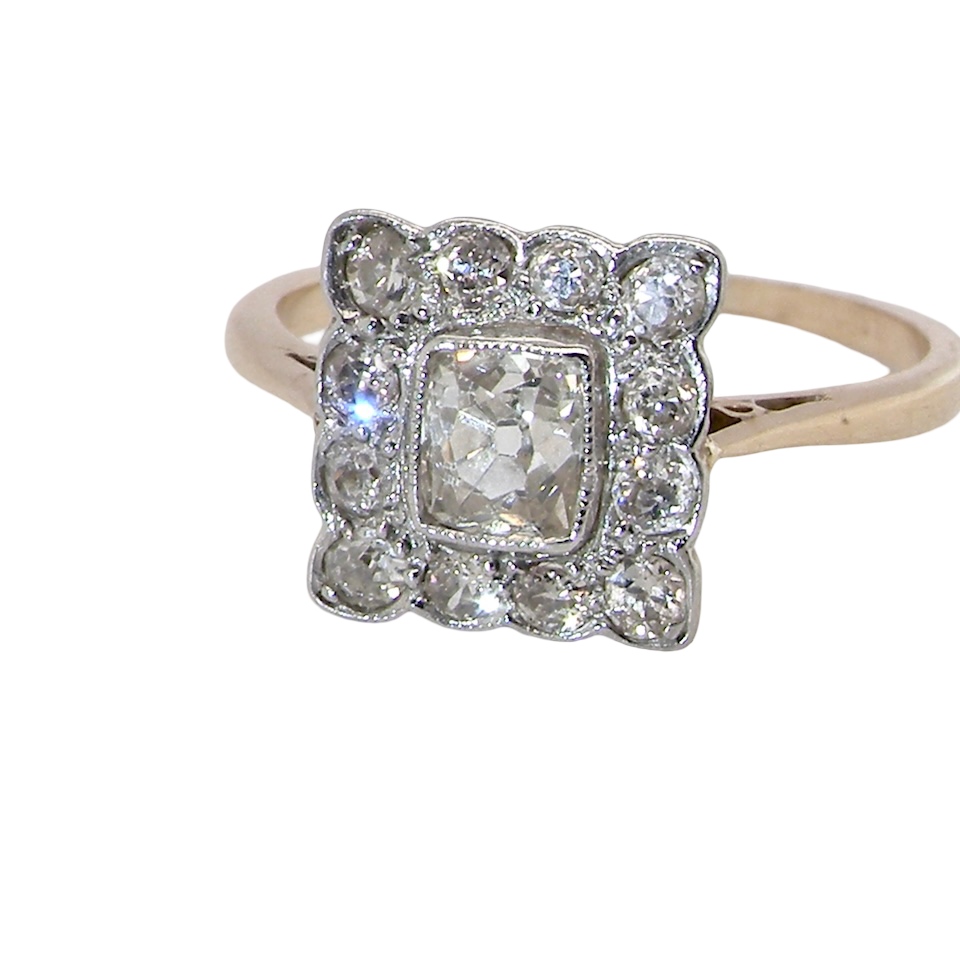 An exquisite Art Deco diamond cluster ring, beautifully handcrafted and rich in period charm.
At its centre sits a striking rectangular cut diamond measuring approximately 5 x 4.8mm, estimated at 0.50 carats,