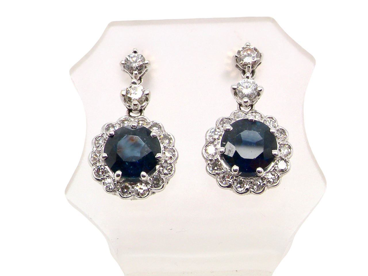 An exquisite pair of drop earrings crafted in 18 carat white gold, each set with a striking inky blue-black sapphire measuring 7.5mm in diameter.