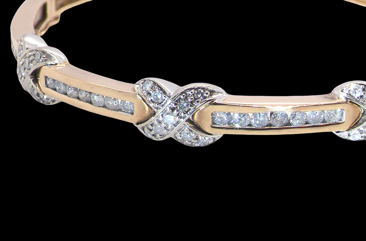 An impressive 9 carat gold bangle.
Three 'kiss' shaped sections , each set with nine brilliant cut white diamonds kiss sections