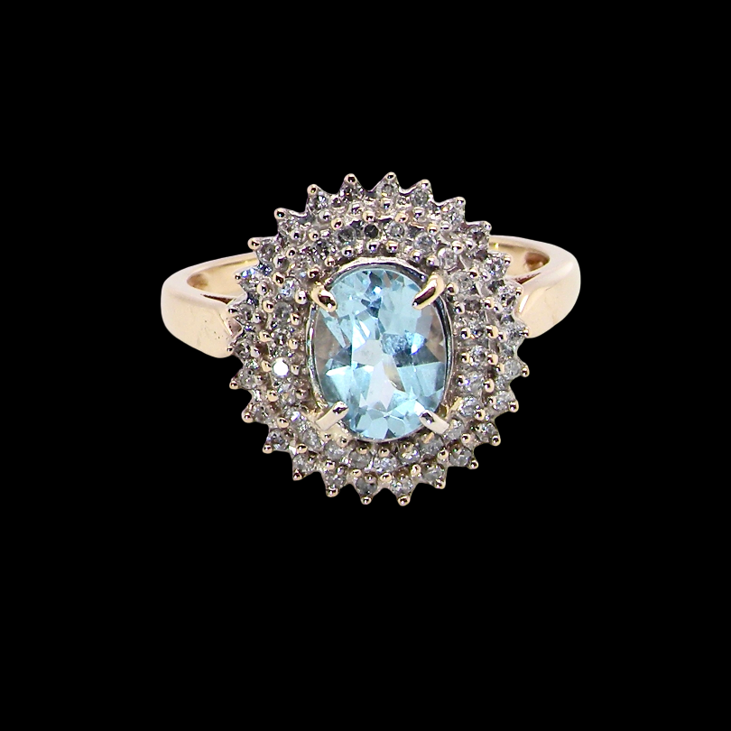 An impressive cluster ring that features to the centre an oval cut blue topaz gemstone, 8x6mm sky blue colour.
Complimented by a double halo of diamonds