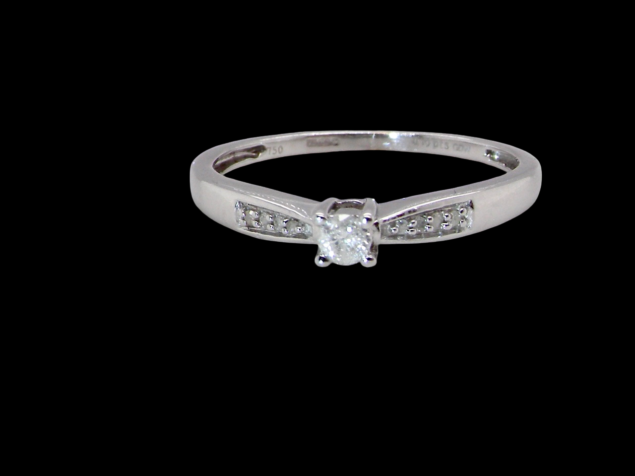 An 18 carat white gold solitaire ring set with a central round brilliant-cut diamond measuring 2.8mm (0.08 carats)