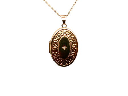 Gold locket with decorative design on a white background