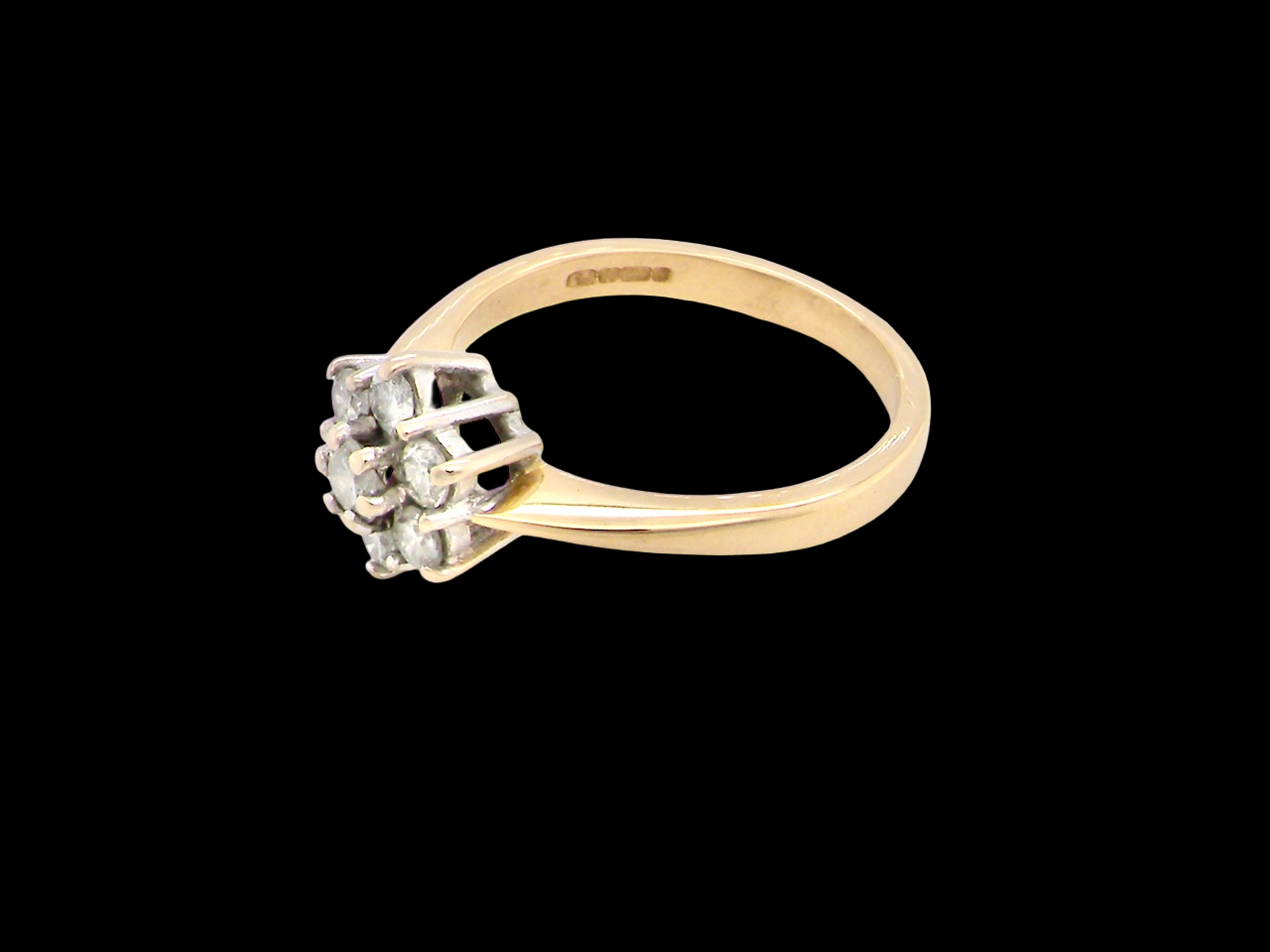 Gold ring with diamond cluster on a black background