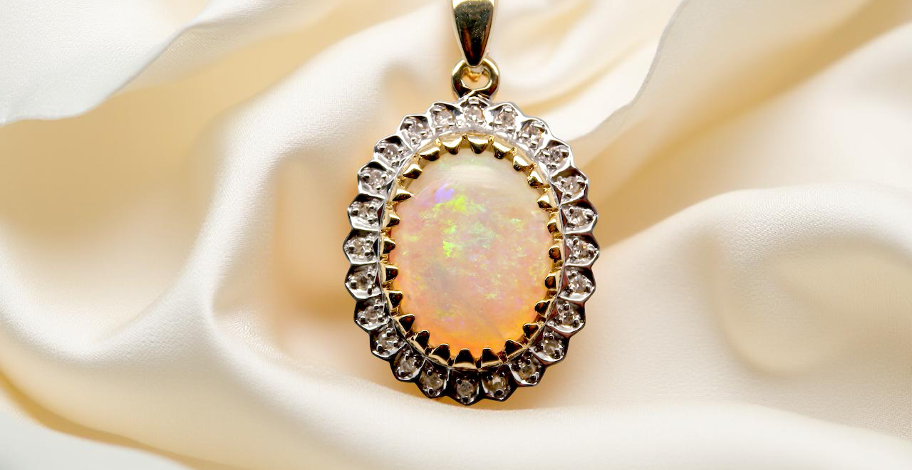 Opal pendant with gold frame and chain on white fabric